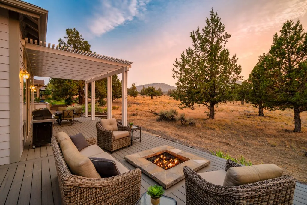 Covered patio with fire pit and seating beside a high-desert view