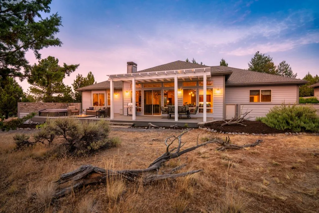 Dusk exterior with covered pergola and warm window light, Sisters Oregon