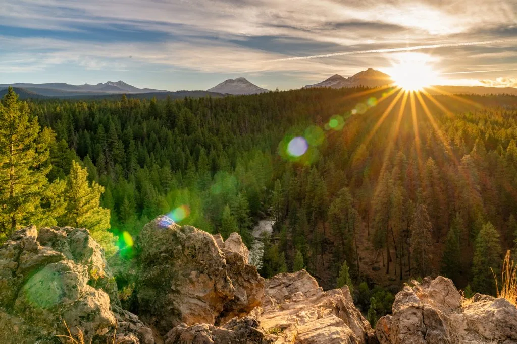 Sun setting over rolling forest and mountain ridgelines