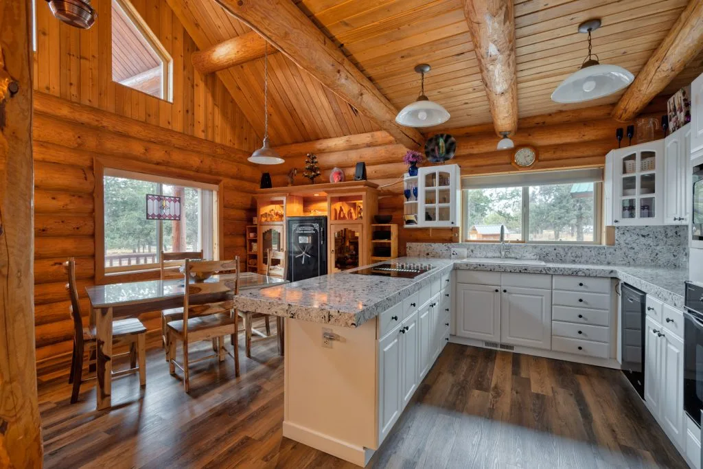 Knotty-pine log cabin kitchen with white cabinets and vaulted ceiling