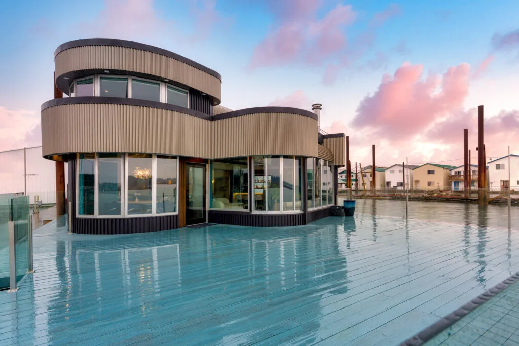 Curved contemporary home wrapping a pool beneath a twilight sky