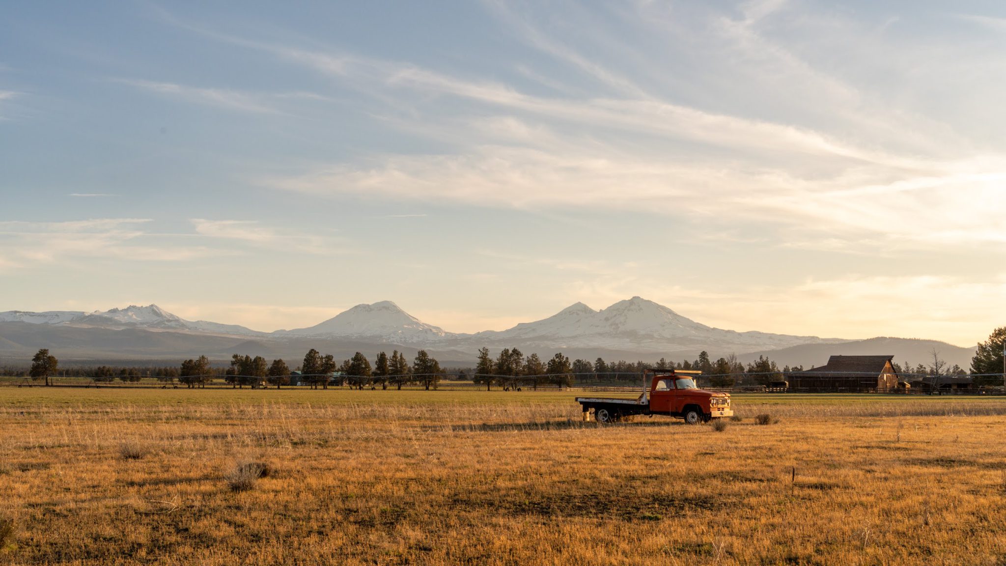 Three Sisters mountains over golden ranch land at sunset near Sisters, Oregon