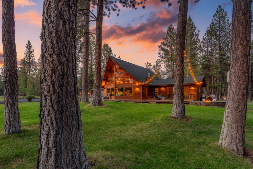 Cabin under towering pines strung with lights at twilight, Bend Oregon
