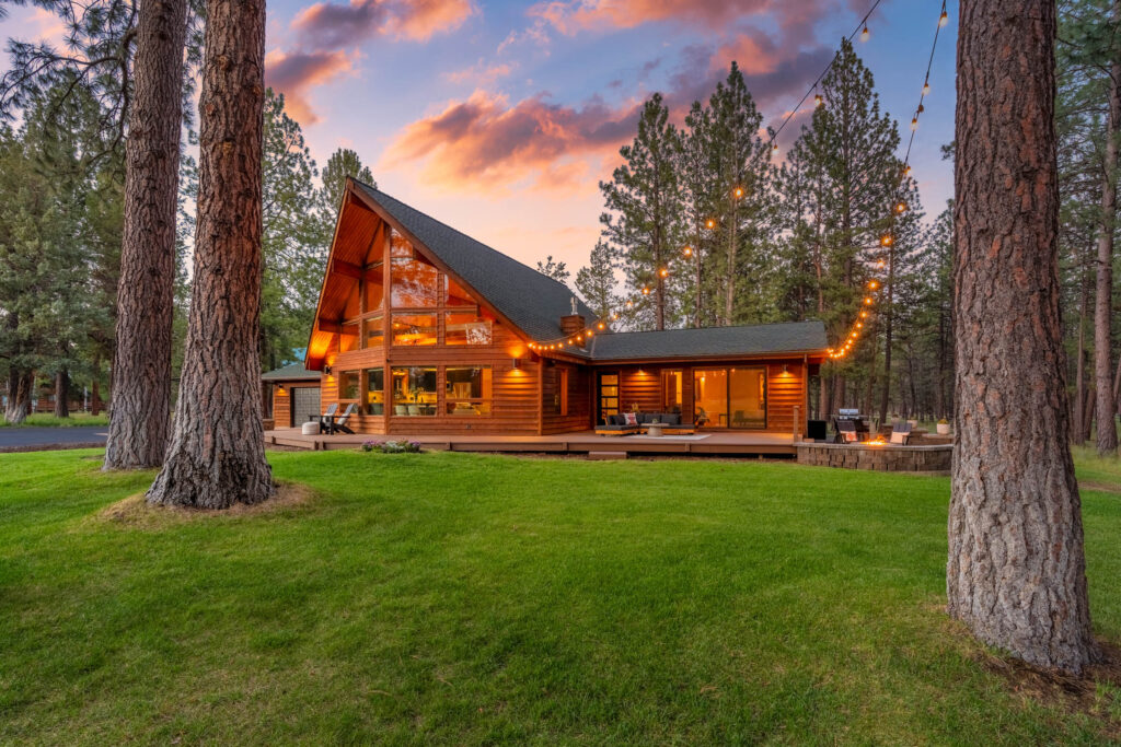 Dusk view of an A-frame cabin with a wall of windows and string-lit deck in Sisters, Oregon