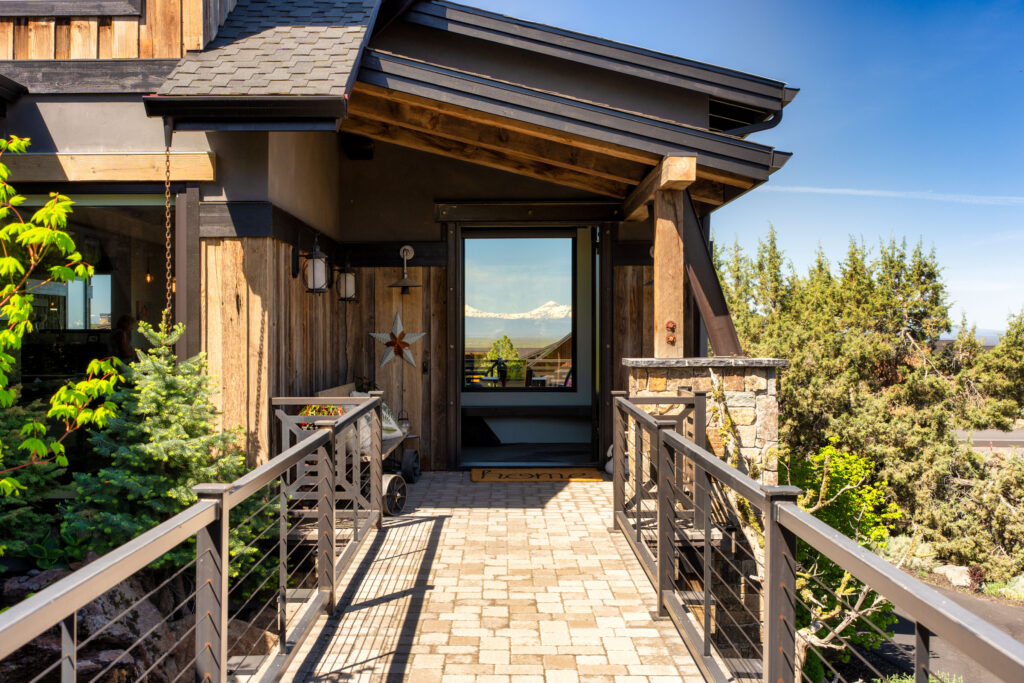 Covered entry bridge leading to a rustic timber home with distant mountain views