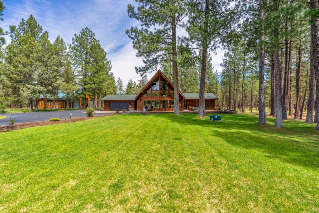 Chalet-style home nestled among ponderosa pines on an expansive green lawn