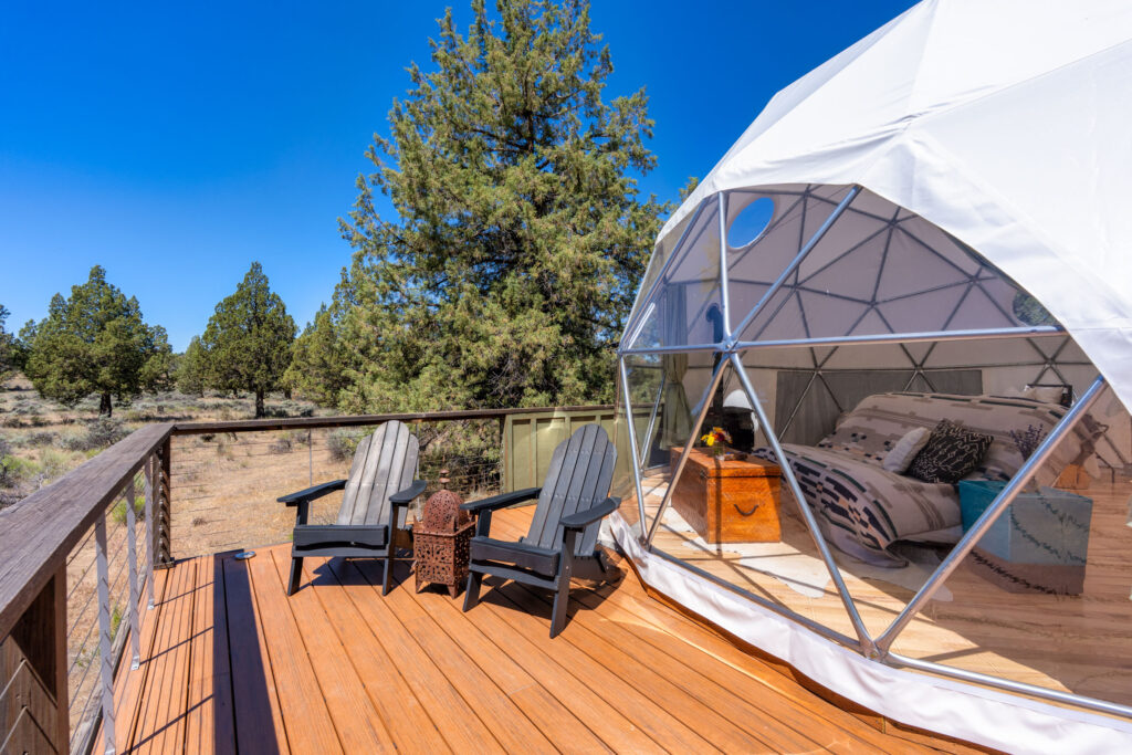 Deck with a geodesic glamping dome bedroom overlooking high desert junipers