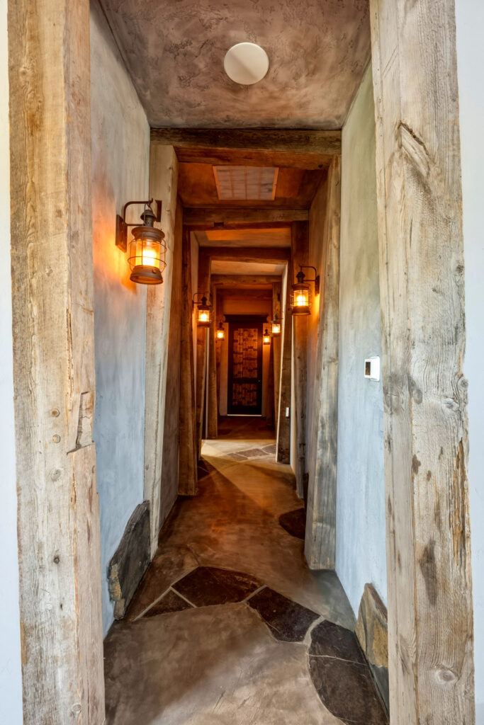 Rustic reclaimed-wood hallway with lantern sconces and flagstone flooring
