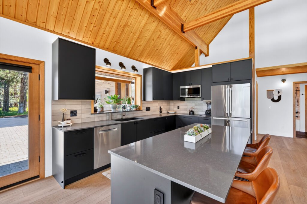 Modern kitchen with charcoal cabinets, gray quartz island and leather barstools