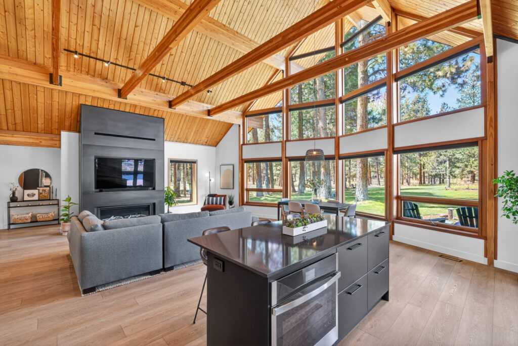 Open-concept living room with vaulted ceiling, wall of windows and dining space