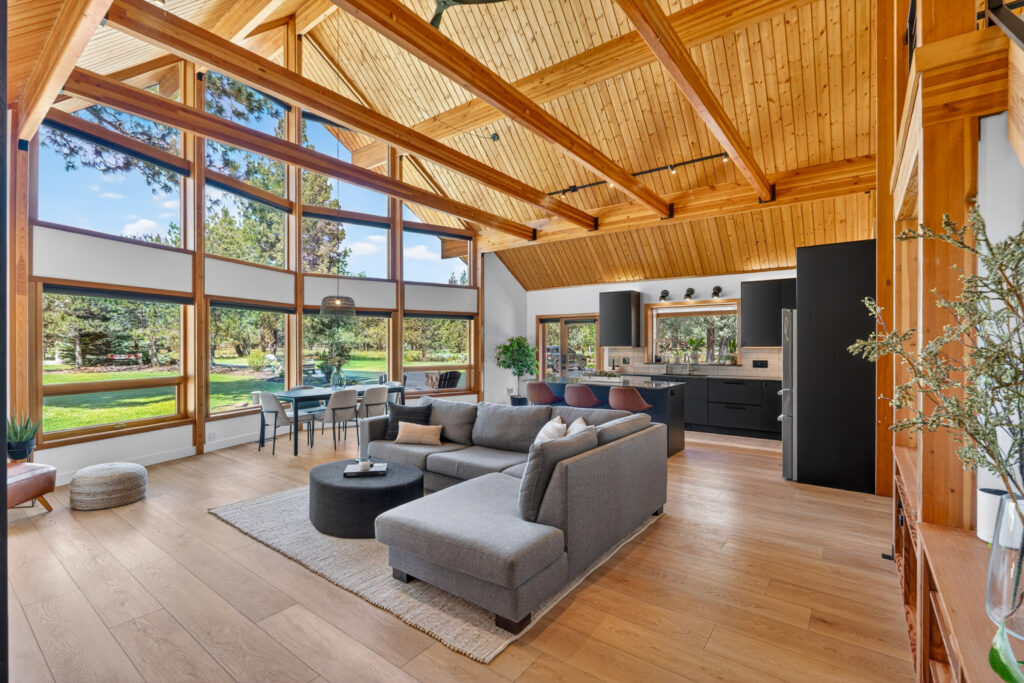 Great room with soaring wood ceiling, wall of windows and green lawn views