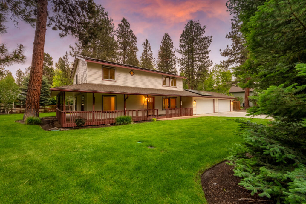 Twilight rear exterior of a two-story home with wraparound porch in Bend, Oregon